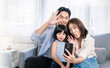 © paulaphoto - Portrait of happy asian family with toddler girl child use smartphone selfie say hi virtual in living room. Happy live online influencer blogger. Technology connected people family lifestyle concept