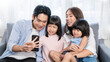 © paulaphoto - Portrait of happy asian family with toddler girl child use smartphone selfie say hi virtual in living room. Happy live online influencer blogger. Technology connected people family lifestyle concept