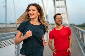 Wall Mural - Early morning workout. Happy couple running across the bridge. Living healthy lifestyle.