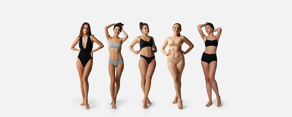 Wall Mural - Five young women wearing underwear standing together isolated over gray background. Body positivity and weight loss concept