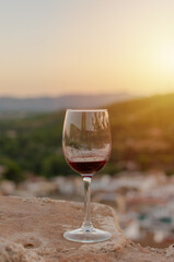 Wall Mural - Close-up of a glass of red wine with a background of mountains with sunset light