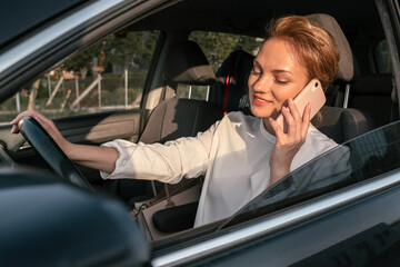 Smiling confident business woman talking on mobile phone driving new comfortable car