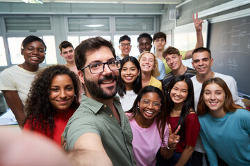 Happy selfie of young group of Erasmus students taking a photo with their teacher in the classroom.