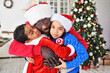 © Evgeniy Kalinovskiy - dad and little children - a daughter and son dressed in a Santa costume with a fake beard hugging and smiling against the backdrop of the Christmas tree.