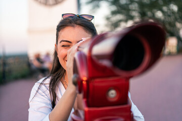 Wall Mural - Pretty Woman tourist looks looks through city binoculars. Travel and tourism concept. Discover new places