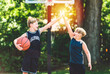 portrait of two boys kids playing with a basketball in park