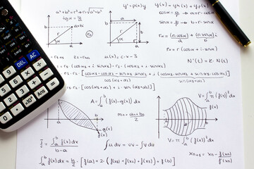 Sheet of paper with science background and math formulas written by hand with calculator and pen.
