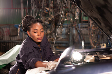 Wall Mural - African american technician female Mechanic working under the hood at the repair garage.