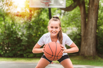 girl with basketball on court on summer season
