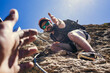 © MIKE FOUQUE - Help and assistance concept. Two people climbing on mountain and helping.