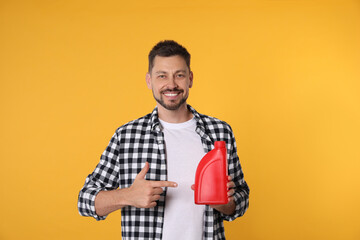 Wall Mural - Man pointing at red container of motor oil on orange background