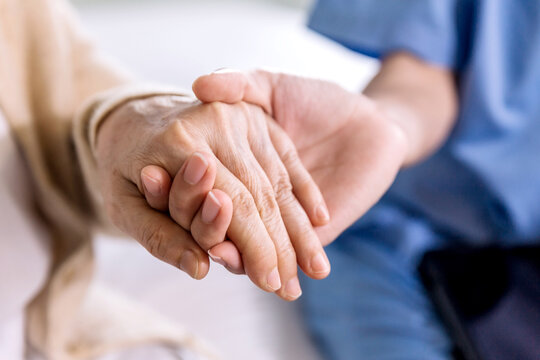 close-up senior asian woman hand with her caregiver helping hands holding together, caregiver visit 