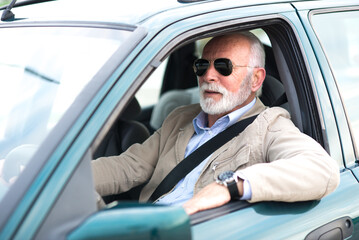 Smiling senior man driving car during day