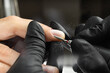Closeup of master hands in black gloves applying an electric nail file drill to remove cuticles in the beauty salon. Perfect nails manicure process. Hardware manicure