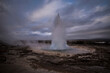 © Cavan Images - Geyser erupting hot spring against cloudy sky