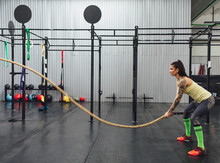 Side View Of Athlete Doing Battle Rope Exercise In Gym