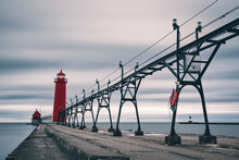 Electricity Pylon And Lighthouse On Pier Amidst Sea Against Cloudy Sky