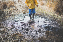 Low Section Of Boy Walking In Dirty Puddle