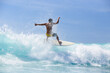 © Cavan Images - Rear view of man surfboarding on waves in sea against sky
