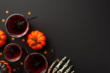 Halloween night party concept. Top view photo of glasses with drink floating spiders straw skeleton hand pumpkins centipede cockroaches and confetti on isolated black background with copyspace