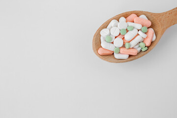 Wall Mural - Many different pills in wooden spoon on white background. Copy space. Top view