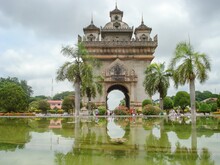Scenic Shot Of The Patuxay Monument In Thailand Surrounded By A Lake And Vegetation