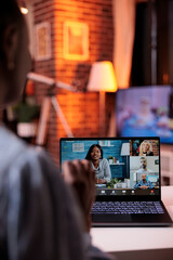 Wall Mural - Young businesspeople having discussion on videoconference, telecommunications and remote teamwork concept. African american female team lead chatting with coworkers using videocall software and laptop