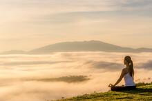 Side View Of Woman Meditating While Sitting On Field By Cloudscape