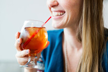 Midsection Of Smiling Woman Enjoying Ice Tea In Cafe