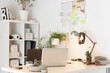 © Cavan Images - Laptop computer on desk with lamp houseplants in creative office