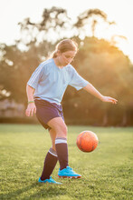 Girl Kicking Soccer Ball While Playing At Field