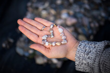 Cropped Hand Of Woman Holding Pebbles In Heart Shape