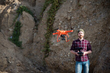 Man flying drone while standing against rock formation