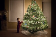© Cavan Images - Side view of boy standing by illuminated Christmas tree at home