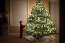 Side View Of Boy Standing By Illuminated Christmas Tree At Home