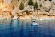 Saint George bay on Symi island, popular stop over for tourists to have a swim in the turquoise waters, Symi island, Greece. Boat sailing at the Symi island and part of the Dodecanese island group.