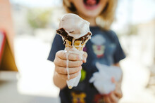 Midsection Of Boy Holding Melting Ice Cream Cone While Standing Outdoors