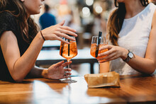 Midsection Of Female Friends With Aperitifs On Table Sitting In Restaurant