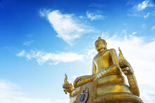 Low Angle View Of Golden Buddha Statue Against Blue Sky During Sunny Day