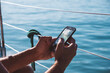 © Cavan Images - Cropped hands of man using mobile phone in boat on sea during sunny day