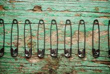 Overhead View Of Safety Pins Arranged On Old Wooden Table