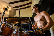 Low Angle View Of Shirtless Drummer Playing Drum While Practicing With Friend In Studio