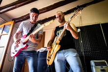 Low Angle View Of Male Guitarists Playing Guitars In Studio