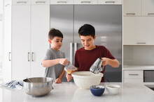 Two boys using a mixer and measuring cup in a modern kitchen