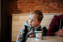 Young Boy Aged 6 Drinking A Hot Chocolate In A Cafe