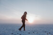 © Cavan Images - girl walks in the winter on a snowy field in a red sweater