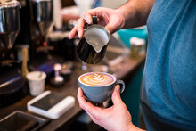 Barista pouring latte behind coffee bar