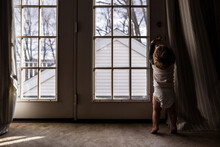 Young Boy In Diaper Reaching Up To Open Door Leading Outside