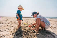Mother And Her Son Playing Together On A Sandy Beach