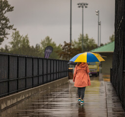 A young woman walking with umbrella on rainy day. Street photo of a woman with colorful umbrella